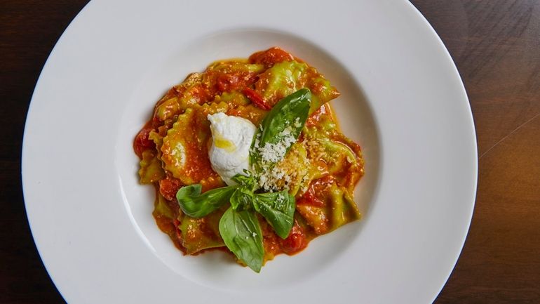 Homemade green pesto ravioli with cherry tomatoes and basil at...