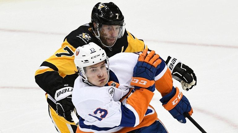 Islanders center Mathew Barzal skates the puck out of the...