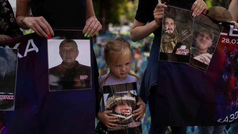 A girl holds a photo of a Ukrainian POW killed...