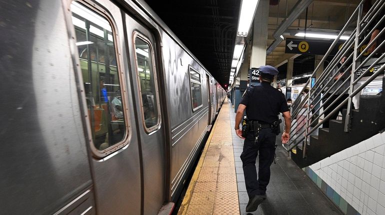 An NYPD officer patrols the Q, N, W, and R,...