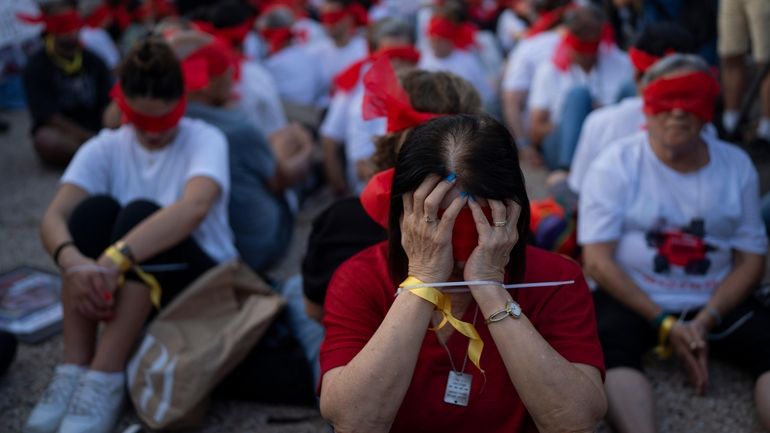 Residents of Kibbutz Kfar Azza bind their hands and wear...