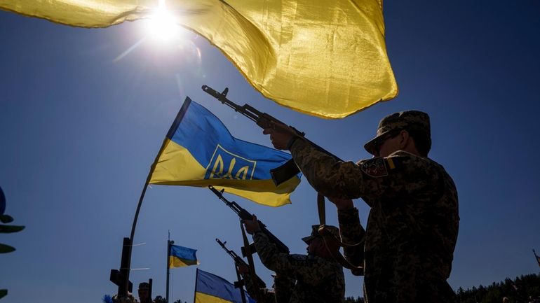 Honor guards shoot into the air during the funeral ceremony...