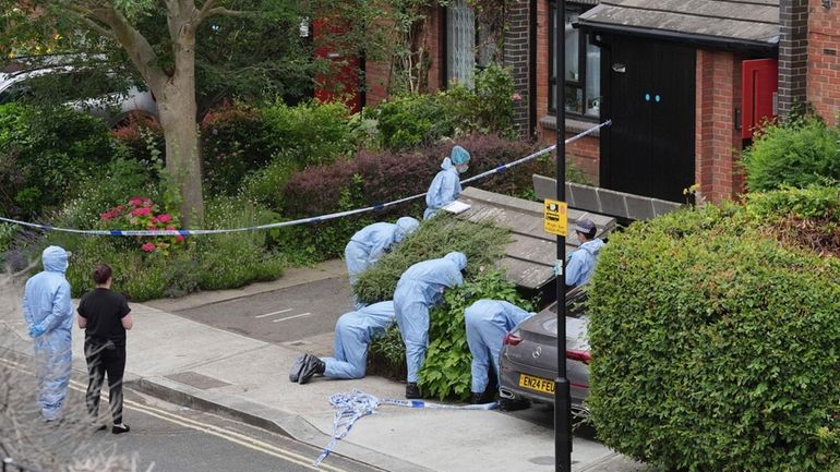 Forensic officers work at an address in Shepherd's Bush, after...