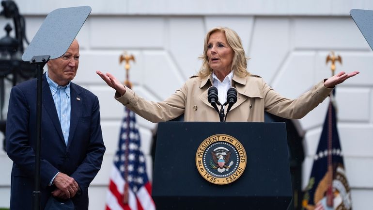 President Joe Biden listens as first lady Jill Biden speaks...