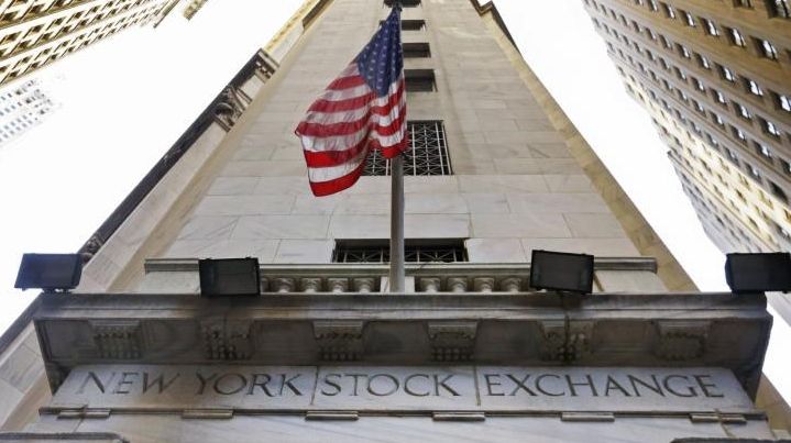 The American flag flies above the Wall Street entrance to...