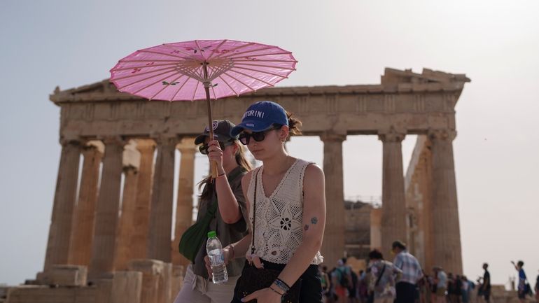 Tourists with an umbrella walk in front of the Parthenon...