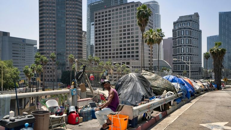 A homeless man sits at his street side tent along...