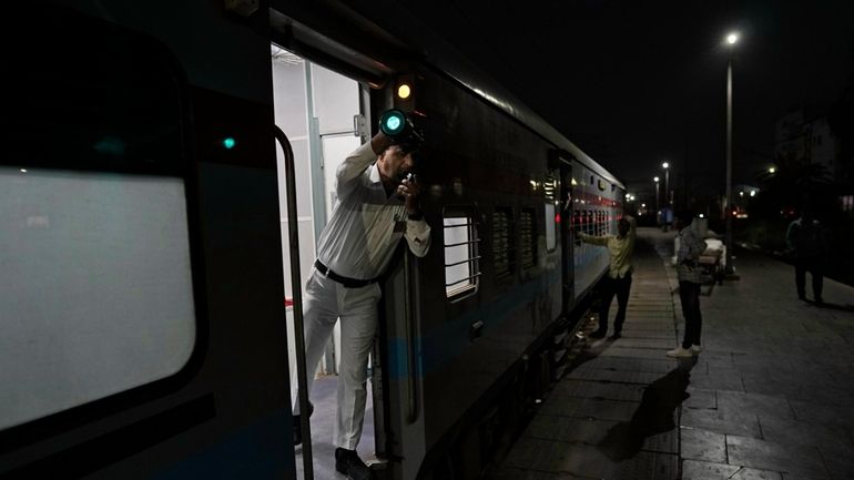 A railway guard shows the signal for the train to...