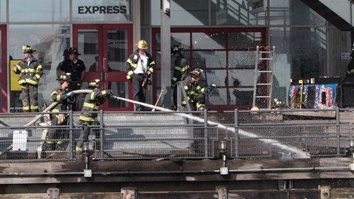 Firefighters work to extinguish a fire at Pier 17 in...
