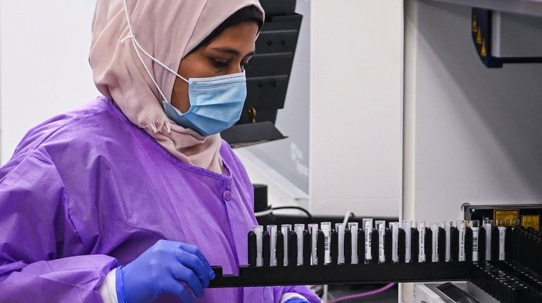 Lab technologist Fardous Choudhury places COVID-19 antibody tests inside the...