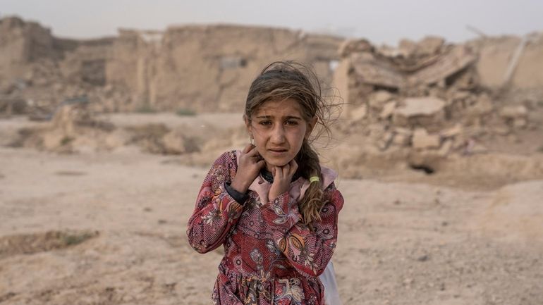 An Afghan girl carries donated aid to her tent, while...