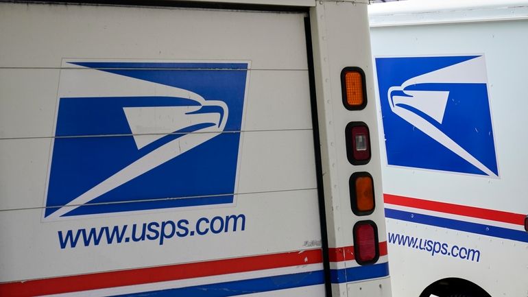 U.S. Postal Service delivery vehicles are parked outside a post...