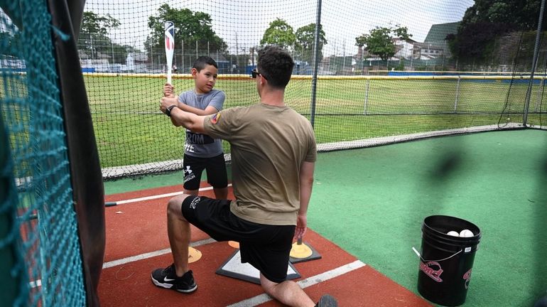 Tyler Stark, 7, gets his first baseball lesson from Zach...