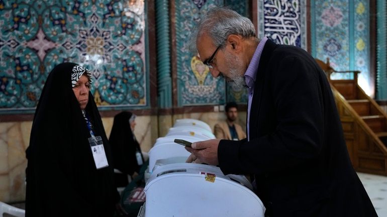 An Iranian man votes for the parliamentary runoff elections at...