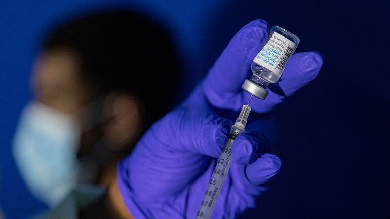 Family nurse practitioner Carol Ramsubhag-Carela prepares a syringe with the...