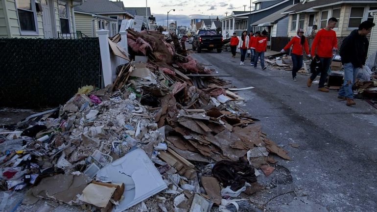 Debris covers Wisconsin Street in Long Beach as the clean...