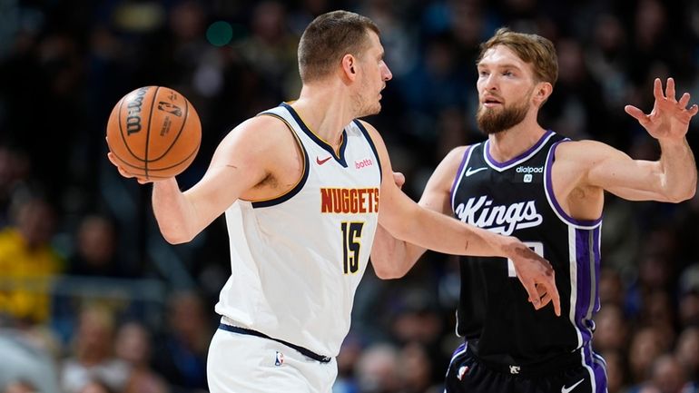 Denver Nuggets center Nikola Jokic, left, looks to pass the...