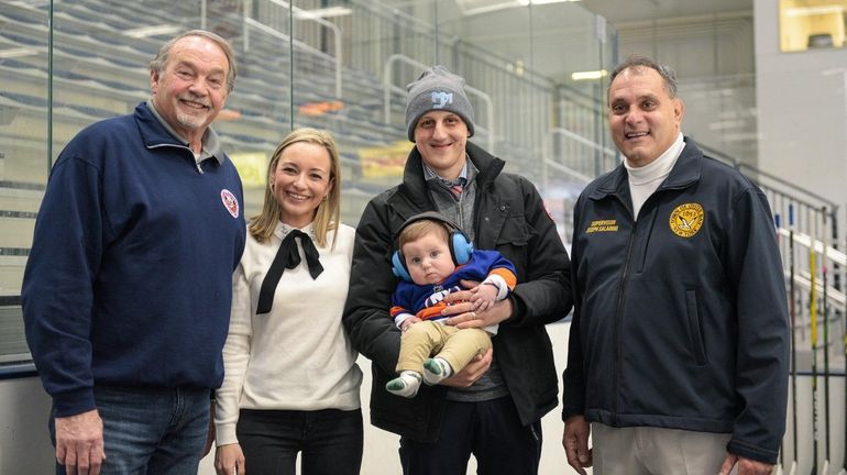 Mike Marcou, coach of Junior Islanders, holds his son Michael...