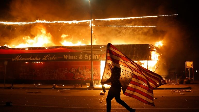 In this May 28, 2020, file photo, a protester carries...