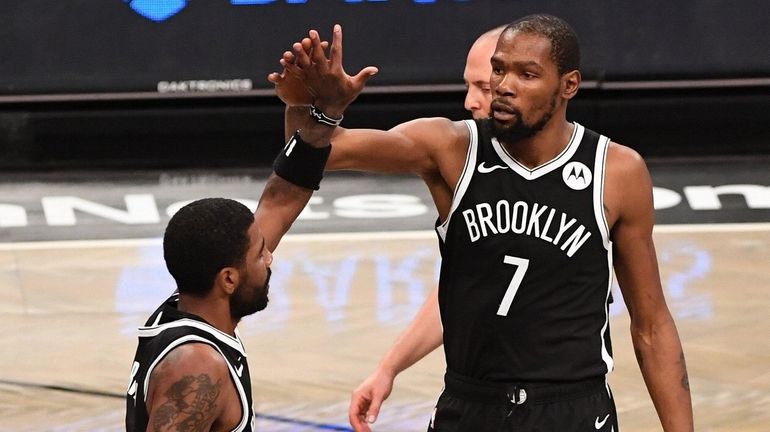 Nets forward Kevin Durant high fives with guard Kyrie Irving...