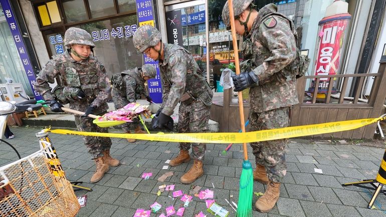 South Korean army soldiers collect the trash from a balloon...