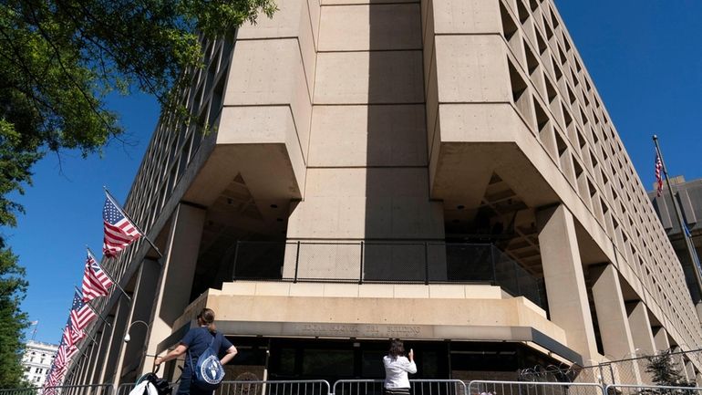 People take photos of the FBI building headquarters in Washington,...