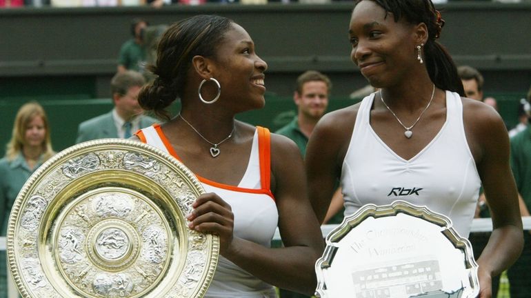 Serena Williams, left, holds her trophy, as she looks over...