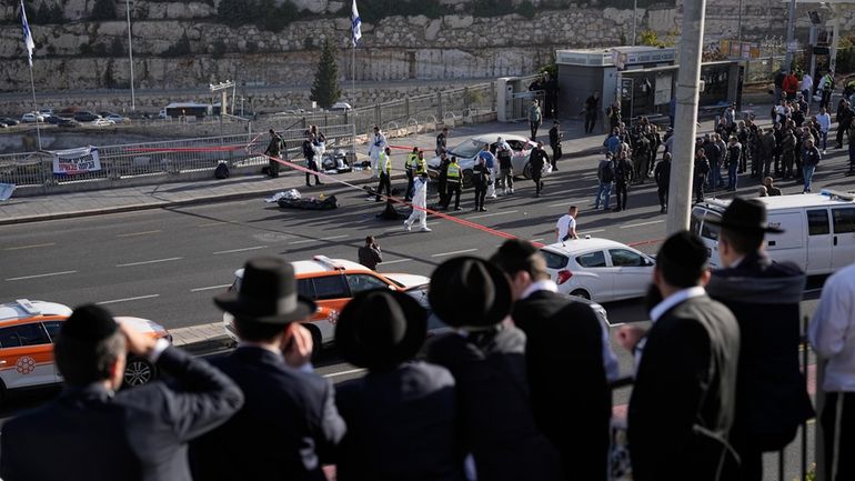 People look at Israeli police officers and volunteers from the...