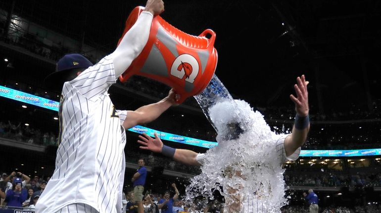 Milwaukee Brewers' Mark Canha, right, is dunked by Willy Adames...