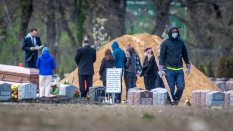 Mourners gather at a small graveside service at Greenfield Cemetery in...