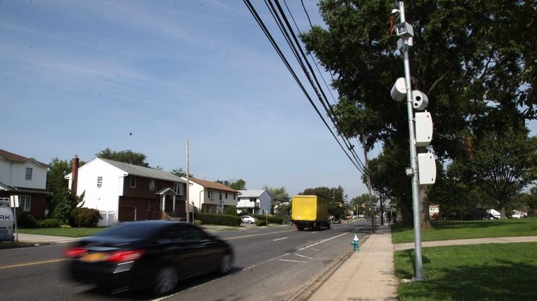 Cars drive past the speed camera set up in front...