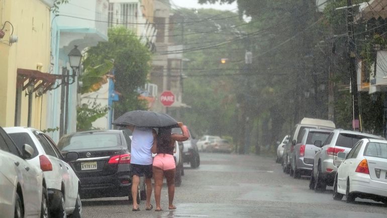 People walk in the rain brought by Tropical Storm Franklin...