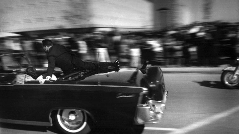 The limousine carrying mortally wounded President John F. Kennedy races...