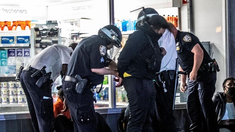 Police officers surround a group of people suspected of looting...