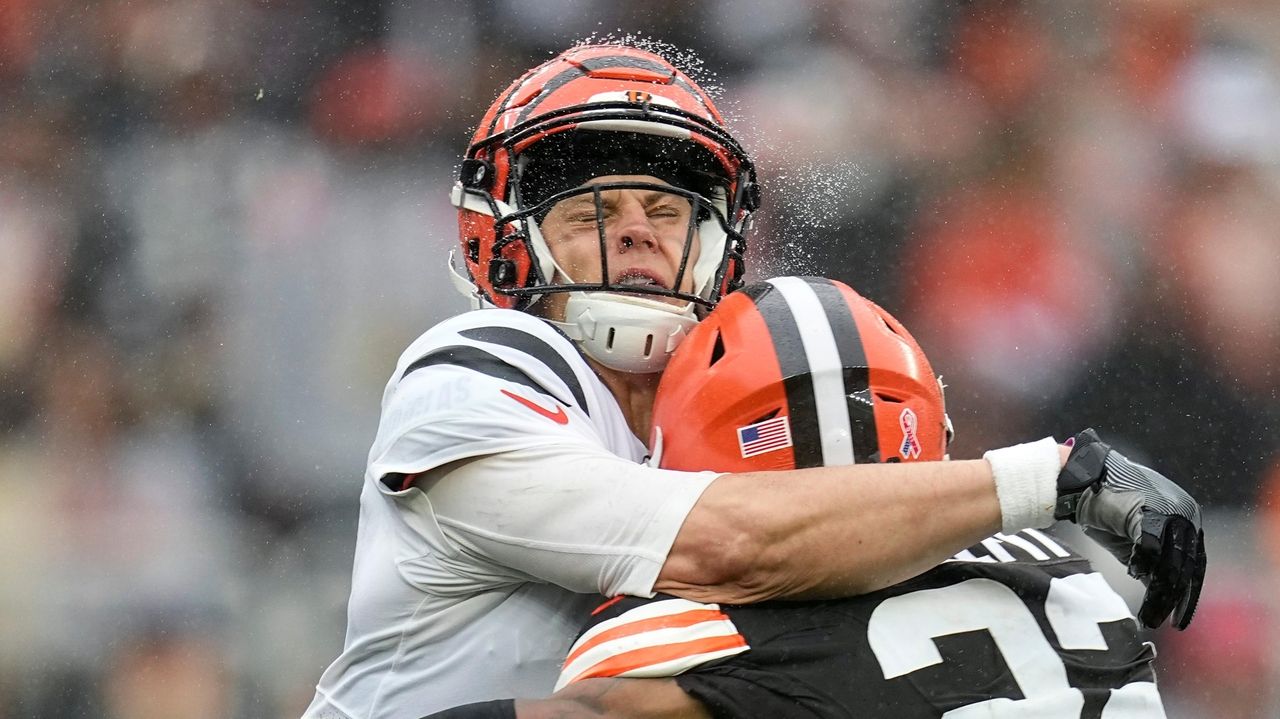 Cincinnati Bengals quarterback Joe Burrow, center, is sacked by