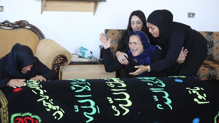 Relatives of the victims weep over the coffins in the...