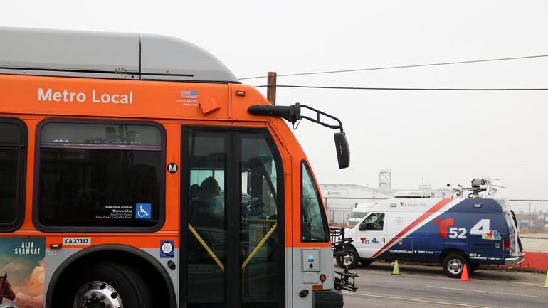 A bus passes by a news van in front of...