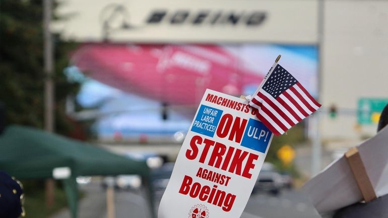 A strike sign is waved on the union machinist picket...