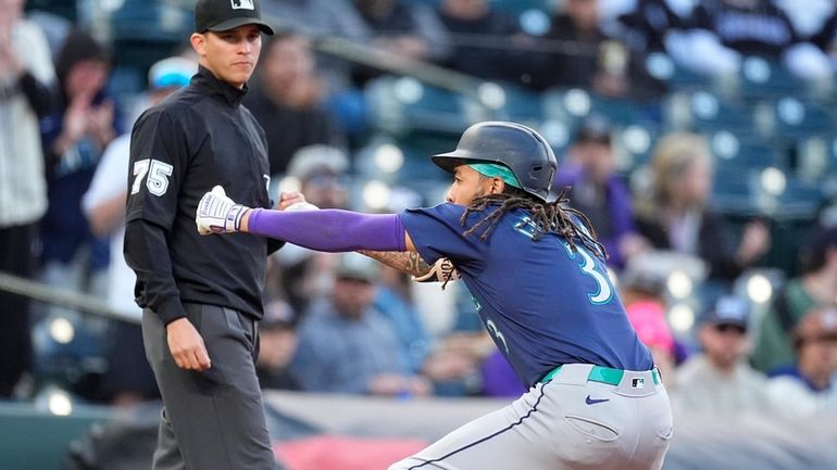 Seattle Mariners' J.P. Crawford, right, celebrates after tripling to drive...