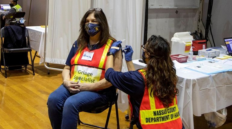 Yessenia Williams gives a COVID vaccine shot to Lorraine Parente...