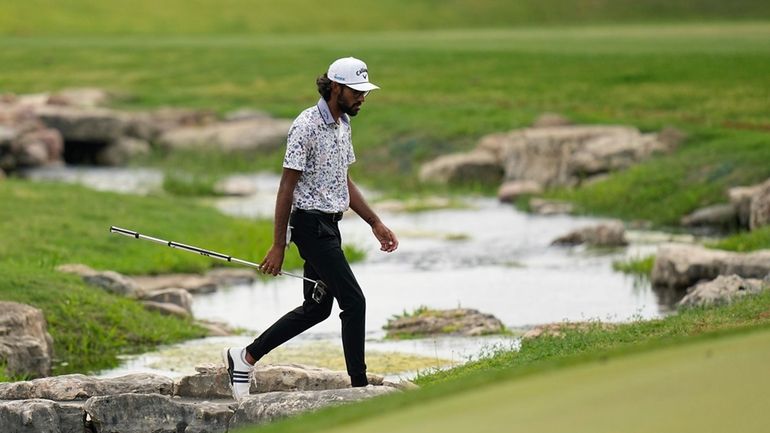 Akshay Bhatia crosses a creek as he walks to the...