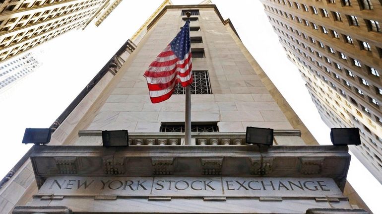 The American flag flies above the Wall Street entrance to...