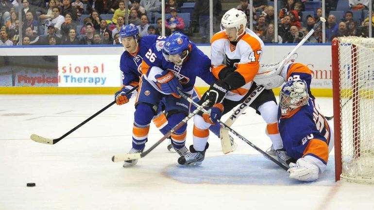 Islanders goalie Evgeni Nabokov tries to move Eric Wellwood of...