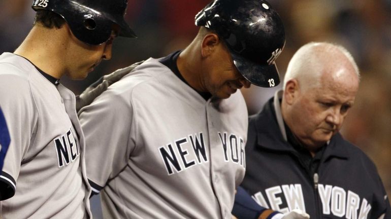 Alex Rodriguez, center, is escorted by teammate Mark Teixeira, left,...