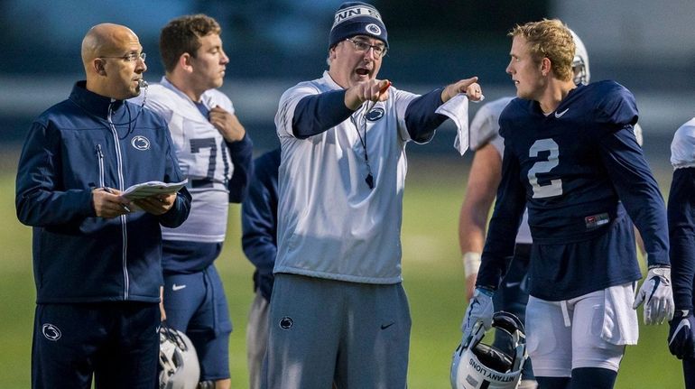 Penn State head coach James Franklin, left, looks on as...