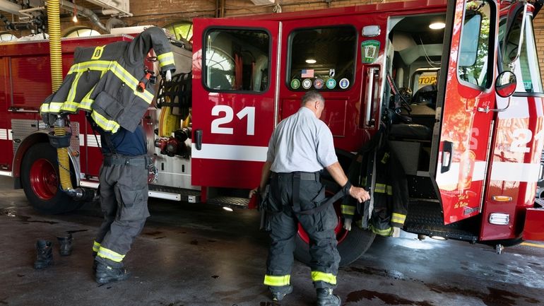 Firefighter Rod MacKinnon, left, and Lt. Chris Stevens don their...