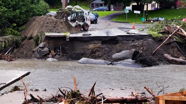 A loader dumps dirt along a washed out portion of...