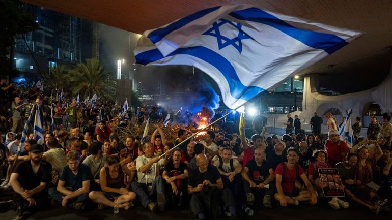 People block a road as they protest, calling for a...