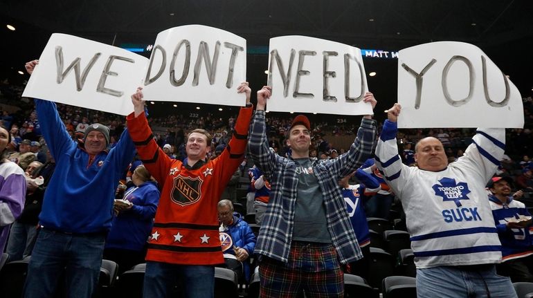 Fans react and hold up banners during player warm ups...