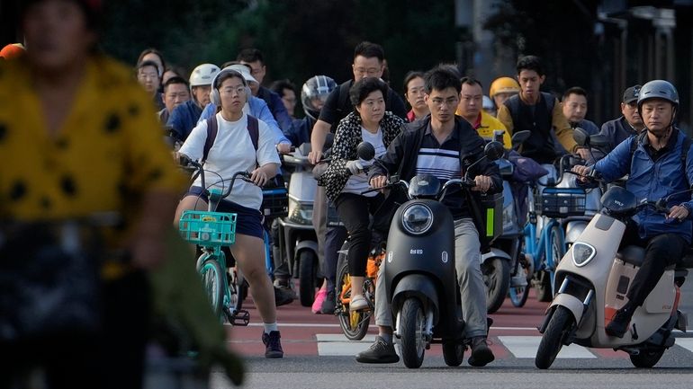 People on their bicycles and electric bikes wait at a...